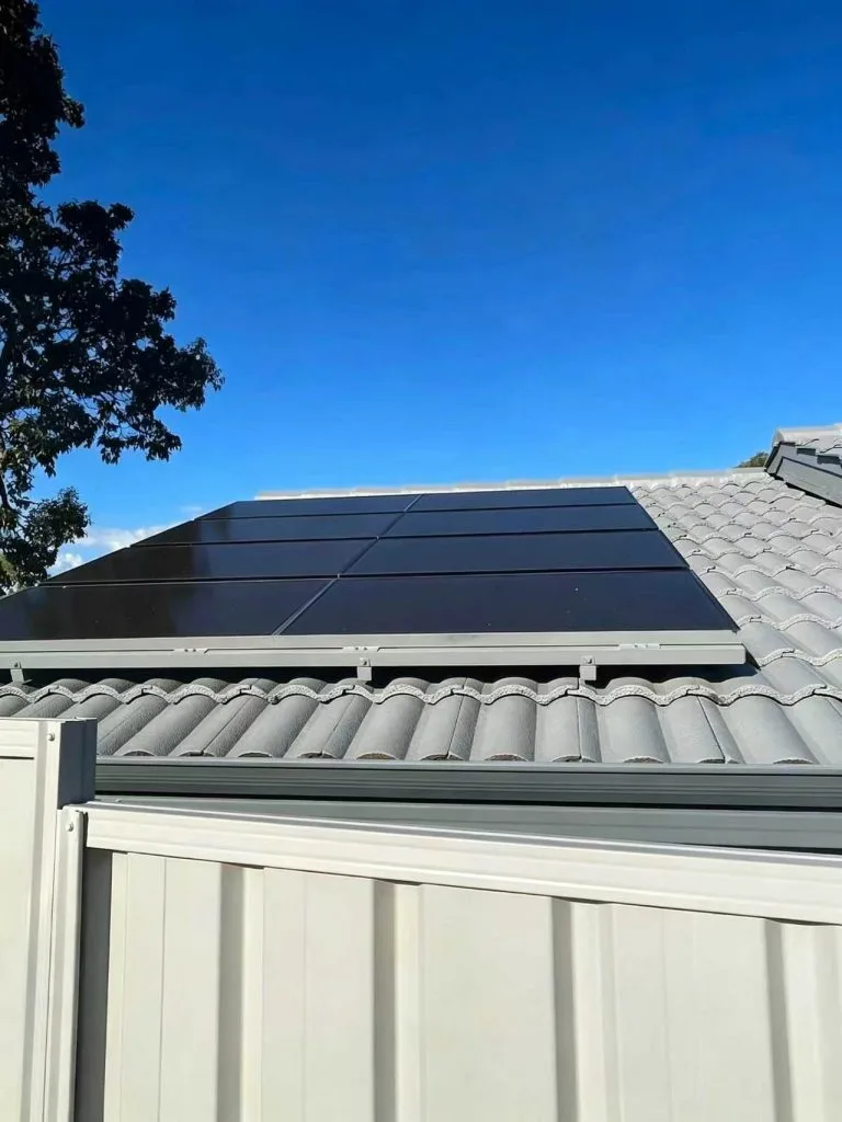Flush-mounted black solar panels on the tiled roof of a Brazilian house under a clear blue sky